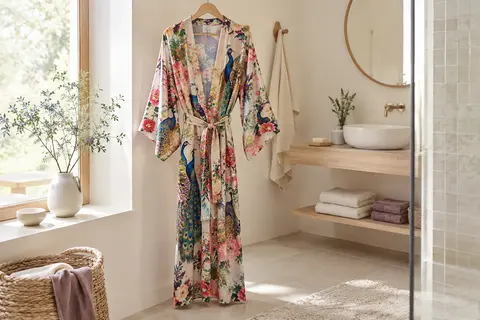 Peignoir kimono long en satin à motif floral et paon, suspendu dans une salle de bain lumineuse