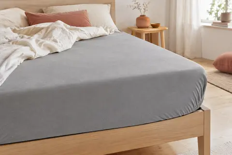 Protège-matelas gris en microfibre brossée installé sur un matelas avec bonnet profond élastiqué