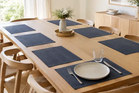 Huit sets de table rectangulaires en PVC bleu foncé disposés sur une table en bois clair