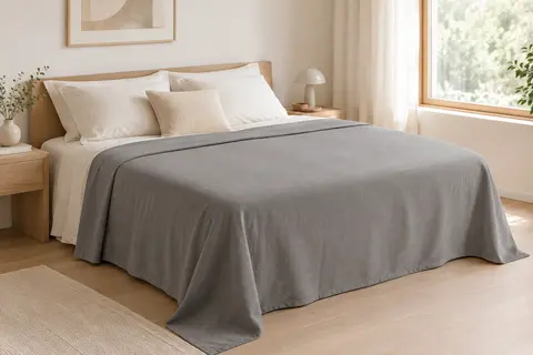 Drap plat gris en microfibre brossée posé sur un lit double dans une chambre claire.